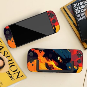 Könnte beinhalten: Eine tragbare Spielkonsole mit schwarzem Bildschirm und einer leuchtend orangefarbenen, roten und dunkelblauen Grafikfolie, die ein drachenähnliches Wesen mit einem leuchtend gelben Auge zeigt. Die Controller-Seiten haben passende Flammenmuster.