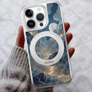 May include: Clear phone case with a dreamy cloud and moon design. The case features a white circular magnetic attachment. The artwork showcases a night sky with fluffy clouds in shades of blue, gold, and white.