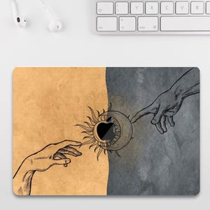May include: A rectangular mousepad featuring a split design with a tan and gray background. The artwork depicts two hands reaching towards a sun and moon design with an apple in the center. The design is a black and white illustration.