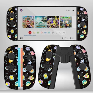 May include: A black Nintendo Switch console with matching Joy-Con controllers. The controllers and console feature a repeating pattern of cartoon characters. The screen displays several game icons. The console is shown with a black grip.
