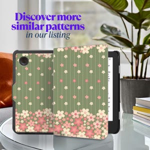 May include: An e-reader with a floral patterned cover. The cover is olive green with white and pink flowers. The text "Discover more similar patterns in our listing" is in the upper left corner.