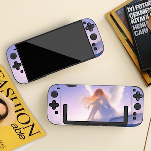 May include: Two Nintendo Switch consoles with custom skins. One has a purple and white sky design, the other an angel illustration with a sky background. The consoles are on a light-coloured surface.