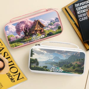 May include: Two rectangular cases with zip closures and handles. One is pink with a landscape scene of a house and a large tree with pink blossoms. The other is white with a landscape scene of a lake and mountains. Both cases have the name "Oliver" on them.