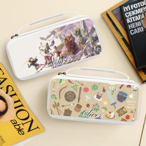 May include: Two white Nintendo Switch carrying cases. One features a colorful fantasy battle scene with the name "Oliver". The other case has a tan background with game-themed icons and the text "Breath of the Wild" and the name "Oliver".