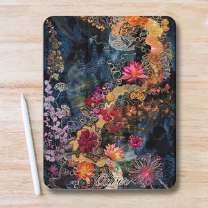Könnte beinhalten: Eine rechteckige Tablet-Hülle mit floralem Design. Die Hülle hat einen dunkelblauen Hintergrund mit bunten Blumen in Rosa-, Orange- und Rottönen. Der Name "Oliver" ist unten in Kursivschrift geschrieben. Auf der linken Seite befindet sich ein weißer Stift.