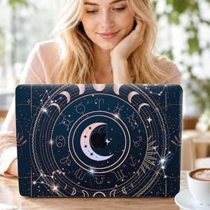 May include: A dark blue laptop skin featuring a celestial design with a central crescent moon, surrounding zodiac symbols, and various moon phases. The design includes thin white lines, star patterns, and a cutout for the central Apple logo.