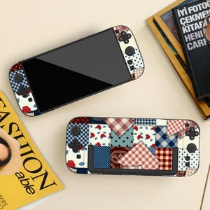 Può includere: Una console di gioco portatile e un controller separato con un design patchwork. Il motivo include quadrati con rose rosse, quadretti vichy blu e bianchi, motivi scozzesi rossi e bianchi, pois neri e texture blu scuro con puntini bianchi.