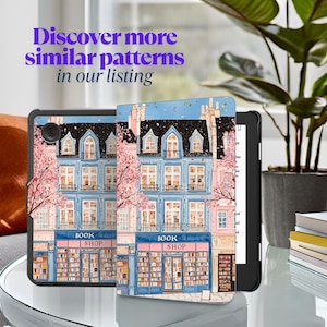 May include: A black e-reader with a colorful cover featuring a watercolor illustration of a bookstore. The cover design includes a blue building with pink accents, cherry blossoms, and the text "BOOK SHOP". The text "Discover more similar patterns in our listing" is also visible.