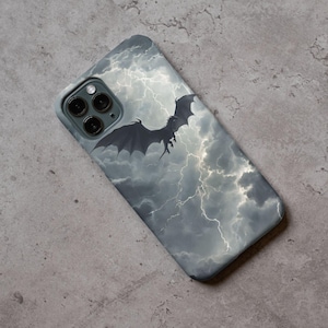 Puede incluir: Funda de teléfono inteligente con un diseño de un dragón oscuro volando a través de un cielo tormentoso con relámpagos. La funda tiene una combinación de colores gris y blanco, con el dragón en silueta. La funda está diseñada para un teléfono inteligente.