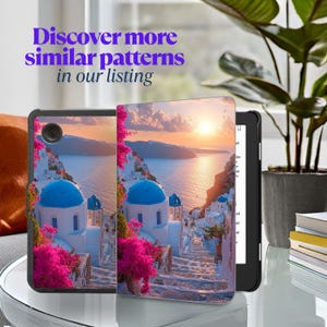 May include: A black e-reader with a cover featuring a scenic view of a coastal town with white buildings, blue domes, and pink flowers. The text "Discover more similar patterns in our listing" is displayed in purple.
