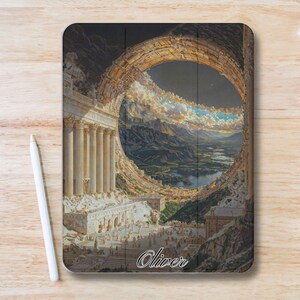 Peut inclure: Une housse de tablette noire avec un paysage surréaliste. L'image présente un grand portail circulaire révélant une chaîne de montagnes, des nuages et un lac. La housse a un design architectural classique avec des colonnes et le nom "Oliver".