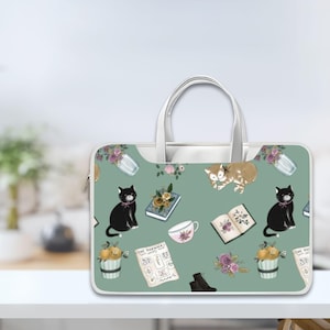 Puede incluir: Una funda para portátil verde con una cremallera y un asa blancas. La funda presenta un patrón repetido de gatos negros, gatos atigrados naranjas, flores, libros, tazas de té y naranjas. El texto "The Bookworm" y "The Post" es visible en la funda.