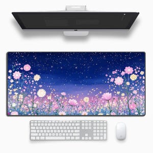 May include: A large rectangular desk mat featuring a floral design with pink, white, and yellow flowers against a dark blue and purple gradient background. A white keyboard, mouse, and computer monitor are also visible.