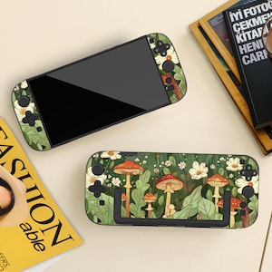 May include: A handheld gaming console with a black screen and a green case featuring a mushroom and floral design. The case has a black stand and control buttons. The design includes white flowers and red-capped mushrooms.