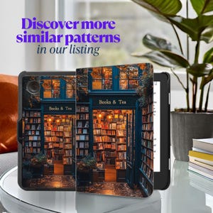May include: A black and gray Kindle e-reader with a colorful case featuring a bookstore storefront with the words "Books & Tea" above the entrance. The storefront is decorated with string lights and has shelves full of books.
