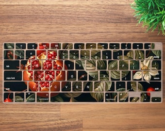 May include: A keyboard cover with a floral design featuring a pomegranate, leaves, and flowers. The design is in shades of red, green, and white on a black background.