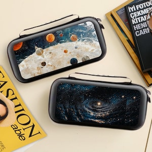 May include: Two black rectangular cases with a white handle and a zip closure. One case has a solar system design, the other a swirling galaxy. The cases are approximately 15 cm long.