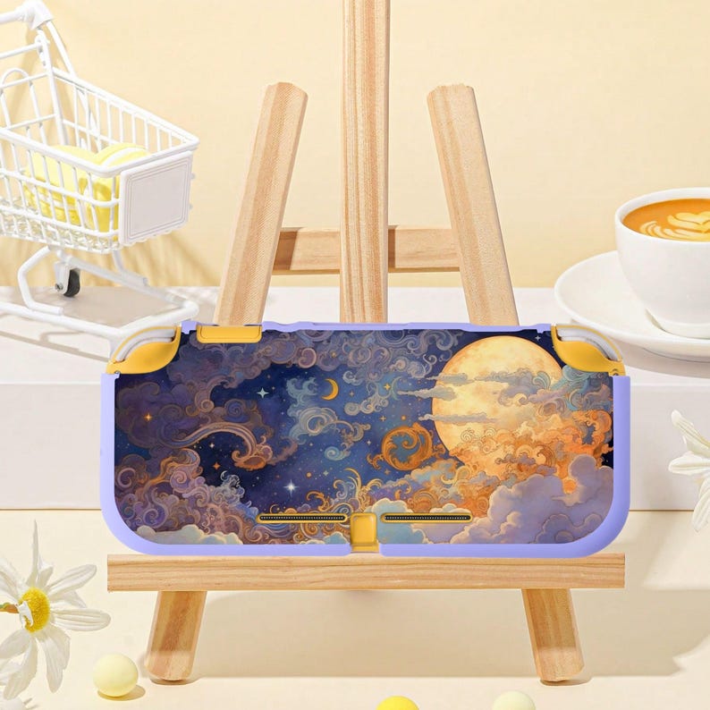 Puede incluir: Una funda lila y dorada para Nintendo Switch Lite con un dise&ntilde;o celestial que presenta una luna llena, nubes y estrellas. La funda se exhibe en un peque&ntilde;o caballete de madera, mostrando su dise&ntilde;o art&iacute;stico.
