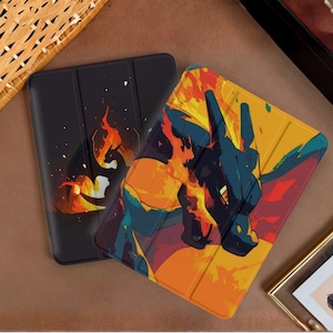 May include: Two rectangular tablet cases featuring a dragon-like creature. One case is black with a small silhouette of the creature surrounded by orange flames. The other case is larger and displays a vibrant, stylized graphic of the creature.