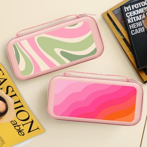 May include: Two pink zippered cases. One features a green, pink, and cream swirl design. The other has a gradient of pink, orange, and red. Both have a small handle and a zipper closure.
