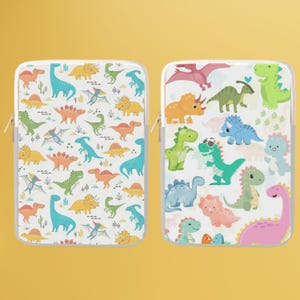 Może przedstawiać: Dwa białe etui na laptopa z kolorowymi wzorami dinozaurów. Jedno etui ma powtarzający się wzór różnych dinozaurów w kolorach pomarańczowym, żółtym, zielonym i niebieskim. Drugie etui ma różnorodne dinozaury w różnych kolorach, w tym różowym, zielonym i niebieskim.