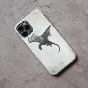 May include: A white smartphone case with a detailed black and grey illustration of a dragon in flight. The dragon has large wings and a long, curved tail. The case has a slightly textured, marbled appearance.