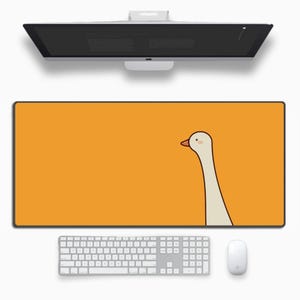 Könnte beinhalten: Ein orangefarbenes rechteckiges Mauspad mit schwarzem Rand zeigt eine Cartoon-Gans mit langem Hals und rotem Schnabel. Eine weiße Tastatur, Maus und ein Computermonitor sind ebenfalls sichtbar.
