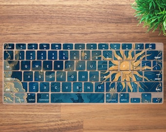 May include: A keyboard cover with a blue and gold sun design. The cover has a blue background with gold accents and a large sun graphic on the right side. The keys are visible with white lettering.