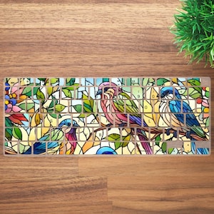 Puede incluir: Funda para teclado con diseño de vidriera que presenta coloridas aves posadas en una rama con hojas verdes. Las teclas son visibles a través de la cubierta transparente, lo que agrega un toque decorativo.