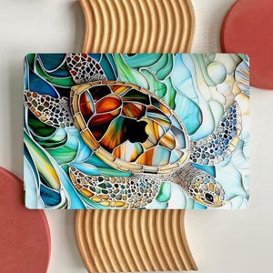 Puede incluir: Una funda para portátil colorida con un diseño de vidriera de una tortuga marina. La tortuga tiene un caparazón marrón, naranja y amarillo, con detalles en azul, verde y blanco. La funda tiene un acabado brillante y un recorte para el logotipo de Apple.