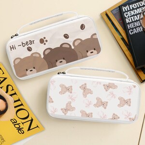 May include: Two white cases with handles. One case features brown bear illustrations with the text "Hi ~bear". The other case has a pattern of small brown teddy bears and pink floral accents. Both cases have a white zipper and handle.