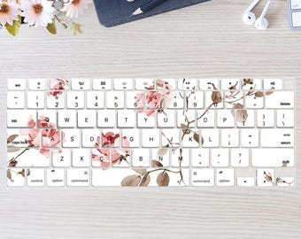 May include: A white keyboard with a floral design featuring pink roses and brown branches. The keyboard has keys for letters, numbers, and symbols. The design is subtle and elegant.
