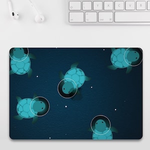 May include: A rectangular mousepad featuring a dark blue background with a pattern of teal turtles wearing space helmets. White dots are scattered across the background. The turtles have a light blue glow around them.
