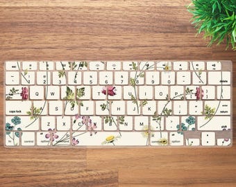 May include: A white keyboard with a floral design. The keys have a clear protective layer with a floral pattern printed on it. The keyboard has a standard layout with keys for letters, numbers, punctuation, and function keys.
