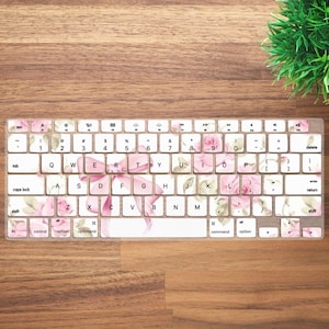 May include: A keyboard cover with a floral design featuring pink roses and a pink ribbon. The cover is made of silicone and is designed to protect the keyboard from spills and dirt.