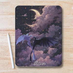 Może przedstawiać: Etui na tablet z fantastyczną ilustracją dwóch smoków lecących na tle nocnego nieba z księżycem w kształcie półksiężyca i gwiazdami. Etui ma fioletowo-czarną kolorystykę, z napisem "Oliver" w skrypcie.