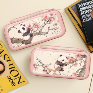 May include: Two pink rectangular cases with a panda bear design. The panda is perched on a tree branch with pink cherry blossoms. The cases have a zipper closure and a small handle.