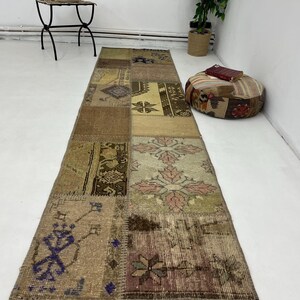 Pode incluir: Um tapete retangular de patchwork com uma variedade de cores e padrões, incluindo marrom, bege e rosa. O tapete é feito de tecido tecido e tem um visual desgastado.