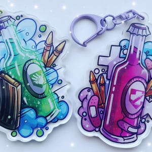 Può includere: Due portachiavi in acrilico con disegni di bottiglie di soda. Uno è verde con un caricatore e la scritta "Speed Cola Soda". L'altro è viola con bende e la scritta "Juggernog Soda". Entrambi hanno proiettili e bolle.