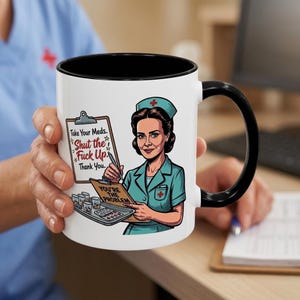 Puede incluir: Una taza de cerámica blanca con asa y borde negros, que presenta un gráfico de una enfermera con uniforme verde azulado sosteniendo un portapapeles. El texto dice: Take Your Meds. Shut the Fuck Up. Thank You. y YOU'RE THE PROBLEM, con una bandeja de medicinas.