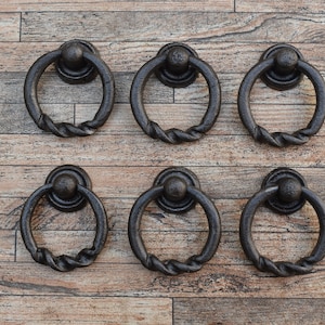 Peut inclure: Six poignées de porte en métal noir avec un design en corde torsadée. Les poignées sont disposées en deux rangées de trois sur un fond en bois.