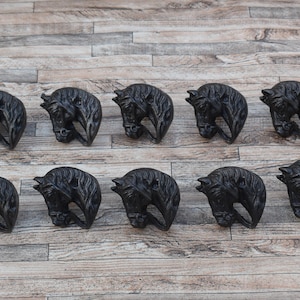 May include: A set of ten identical black metal cabinet knobs, each shaped like a detailed horse head in profile. The knobs feature a textured finish with visible mane and facial features, designed for attachment to furniture or cabinetry doors.