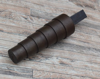 Peut inclure: Un mandrin à anneaux en métal brun foncé avec une poignée en métal noir. Le mandrin est composé de plusieurs anneaux qui se rétrécissent en pointe.