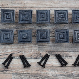 Op de afbeelding: Tien zwarte vierkante kastknoppen met een spiraalvormig ontwerp en acht zwarte schroeven.