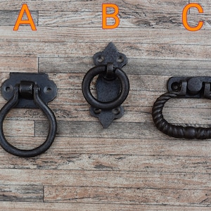 Peut inclure: Trois poignées de porte en métal noir de styles différents. Les poignées sont sur un fond en bois. Les poignées sont étiquetées A, B et C.