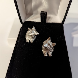 May include: Two silver fox cufflinks in a black velvet box. The cufflinks are detailed and realistic.