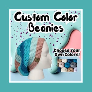 May include: A handmade crochet beanie in shades of blue, teal, and tan, displayed on a mannequin head. The text "Custom Color Beanies" and "Choose Your Own Colors!" are visible. The beanie has a small brown tag.
