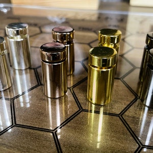 Pode incluir: Um conjunto de oito suportes de exibi&ccedil;&atilde;o decorativos de metal em acabamentos prata, dourado e preto. Os suportes est&atilde;o dispostos em um padr&atilde;o hexagonal sobre uma superf&iacute;cie de madeira.