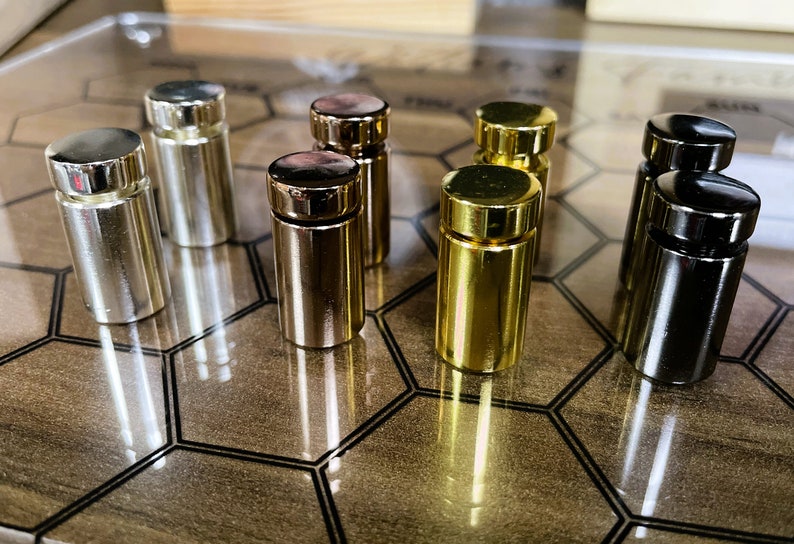 Pode incluir: Um conjunto de oito suportes de exibi&ccedil;&atilde;o decorativos de metal em acabamentos prata, dourado e preto. Os suportes est&atilde;o dispostos em um padr&atilde;o hexagonal sobre uma superf&iacute;cie de madeira.