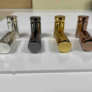 Pode incluir: Quatro suportes de exibi&ccedil;&atilde;o de metal em diferentes acabamentos: prata, preto, dourado e ouro rosa. Os suportes s&atilde;o cil&iacute;ndricos e t&ecirc;m uma parte superior arredondada.